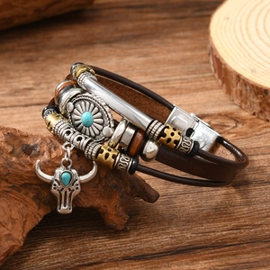 Macro detail of leather bracelet featuring bull head pendant and steel clasp on wood texture