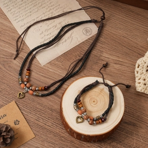 Retro multi-layer woven heart pendant necklace and bracelet set on vintage wood background