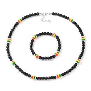 Detail of matte black beaded jewelry set with red, yellow, and green accent beads
