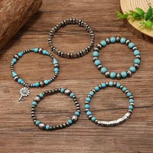 Five-piece bohemian turquoise bead bracelet set with ethnic silver charms on wood