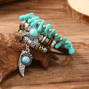 Detail of bohemian multilayer leather bracelet with turquoise beads and carved metal charms
