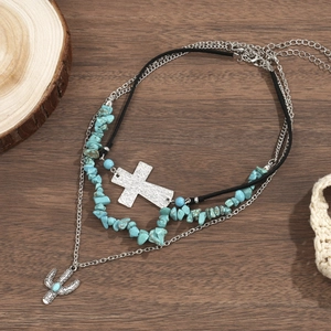 Detail van bohemien gelaagde ketting met turquoise kralen en zilveren kruishanger