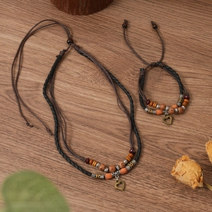 Close-up of vintage multi-layer woven heart pendant necklace with wood beads on wood