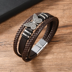 Detailed macro view of multilayer braided leather bracelet with vintage butterfly charm