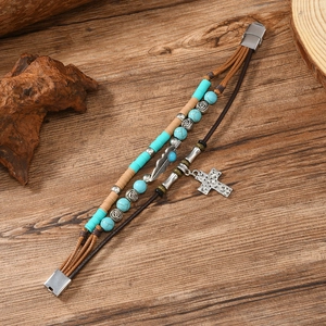 Detail of bohemian leather bracelet with turquoise beads, feather charm and cross pendant