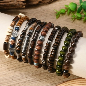 Detail of stacked bohemian wood bead bracelets with Tree of Life charms on rustic background