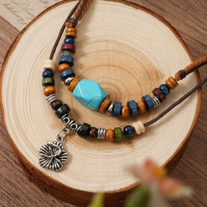 Ethnic retro beaded necklace with turquoise stone and silver flower pendant on wood
