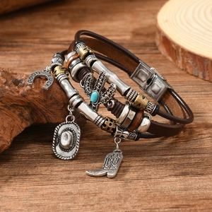 Close-up of Western cowboy leather bracelet with cactus, cowboy hat and horseshoe charms