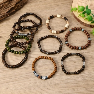 Detail of bohemian wood bead bracelets with metallic Tree of Life charms on wooden surface