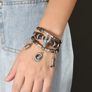 Detail of multi-layer leather bracelet with western cowboy pendants and turquoise cactus