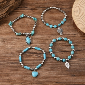 Bohemian turquoise bead bracelet set with cactus, feather, and heart pendants on wood surface