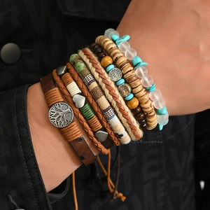 Close-up of bohemian layered bracelets with turquoise, tree of life charm, and leather cords
