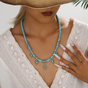Bohemian turquoise beaded necklace featuring vintage silver leaf pendants on a female model