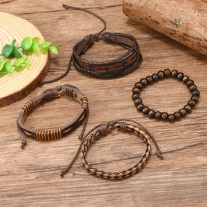 Detail view of four-piece vintage leather bracelets with wooden beads on wooden texture