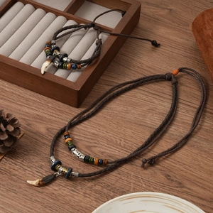 Ethnic wolf tooth pendant necklace and bracelet set on a rustic wooden surface detail