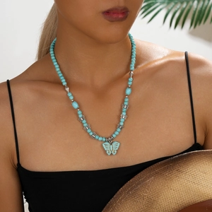 Collier bohème en perles turquoise avec pendentif papillon porté par mannequin style vacances d'été