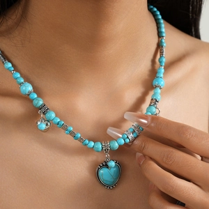 Collier bohème avec pendentif cœur en turquoise et perles argentées porté par mannequin
