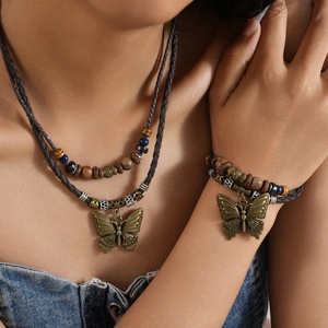 Detailed view of layered woven leather necklace with bronze butterfly pendant and beads