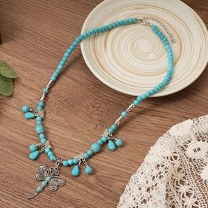 Detailed shot of bohemian turquoise beaded necklace with metal dragonfly and butterfly charms