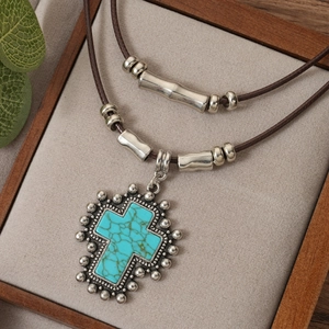 Vintage double-layer necklace featuring a turquoise cross pendant and rustic leather cord