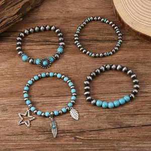 Detail of bohemian stackable beaded bracelets with star and feather charms on wood