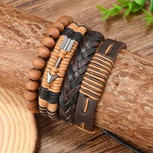 Detail of four stackable bohemian bracelets with leather, wood beads, and woven ropes on wood