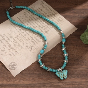 Détail du collier bohème en perles de turquoise avec pendentifs papillon en argent