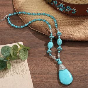 Bohemian turquoise beaded necklace featuring a large teardrop pendant and vintage metal spacers