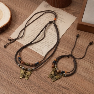 Detailed close-up of retro woven necklace with bronze butterfly charms and wooden beads