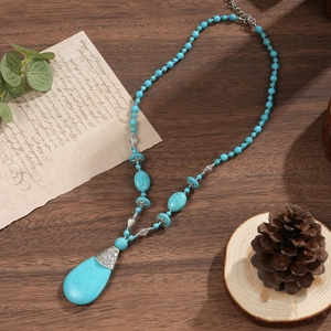 Detail of bohemian turquoise beaded necklace with water drop pendant on vintage wood background