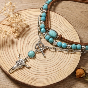 Detail van bohemien ketting met turquoise kralen en zilveren stierkop hanger op hout