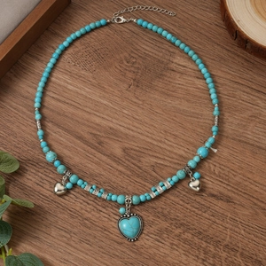 Gros plan d'un collier bohème en turquoise avec pendentifs cœurs et perles sur bois