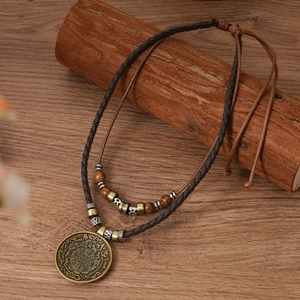Détail du pendentif en bronze vintage sur cordon en cuir avec perles en bois et motifs