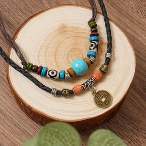 Close-up of ethnic beaded necklaces with turquoise, totem beads and ancient bronze coin