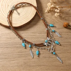 Macro detail van boho gelaagde ketting met turquoise kralen en zilveren veerhangers