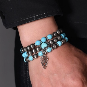 Detail of bohemian layered beaded bracelet with turquoise heart and hollow geometric pendant