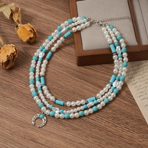 Detail of three-layer necklace with faux pearls, turquoise beads and crescent pendant