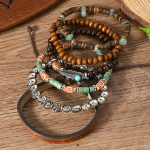 Detail of bohemian stacked bracelets featuring wood beads, stone accents, and feather charm