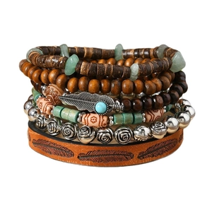 Detail of bohemian layered beads bracelet with wood, stone charms and a leather feather cuff