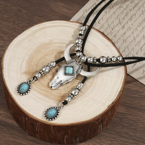 Vintage bull skull pendant necklace with turquoise stones on a rustic wood background