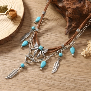Detail van bohemien ketting met turquoise kralen en veerhanger op hout