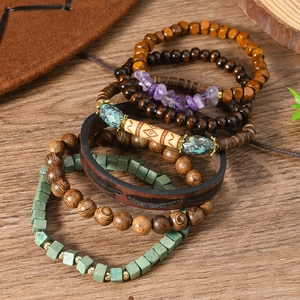 Detail of bohemian multilayer bracelets with wooden beads and leather feather strap