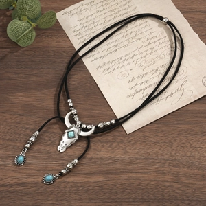 Detail of bohemian bull skull necklace with turquoise stones on dark wooden background