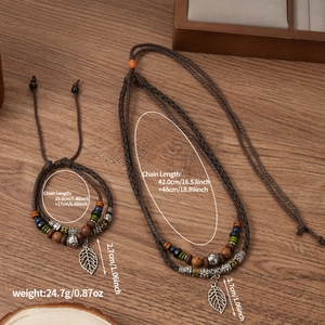 Detailed view of woven rope necklace with leaf pendants and wooden beads on wood background