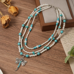 Macro detail of multilayer pearl and turquoise necklace with dragonfly pendant