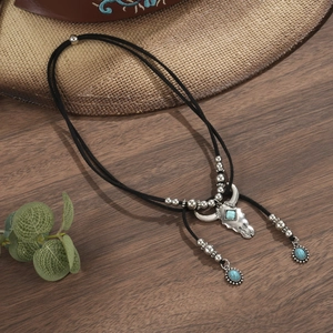 Macro detail of western bull head pendant with turquoise on rustic wood and straw background