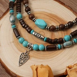 Collier bohème à trois couches en perles de bois et turquoise sur un support en bois