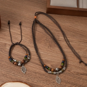 Detail of vintage bohemian necklace with wooden beads and a hollow leaf metal pendant