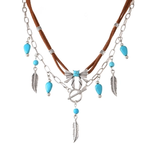 Detail van boho gelaagde ketting met turquoise kralen, zilveren veren en OT-sluiting