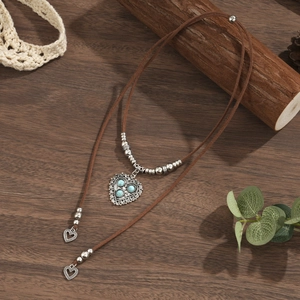Macro view of a double-layer boho choker with heart pendant and turquoise stone inlays